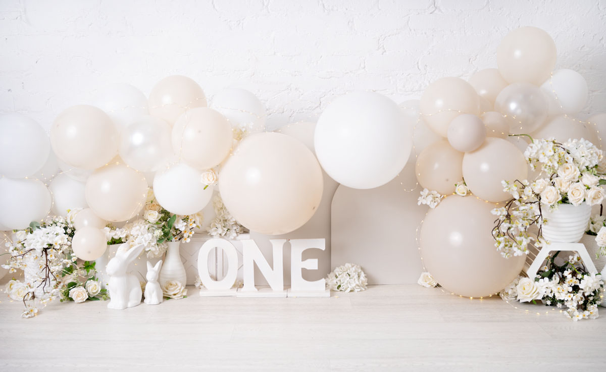 nude and white cake smash photoshoot setup with balloons and flowers