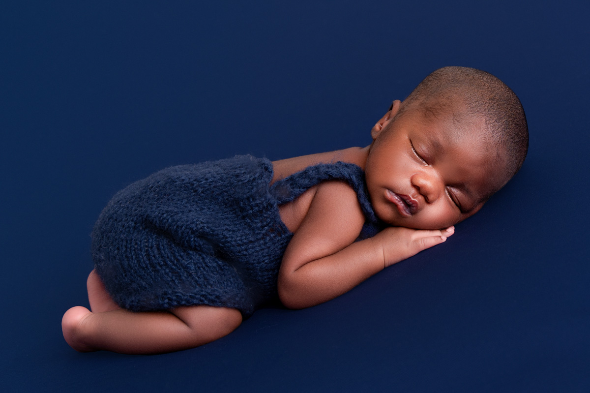 baby sleeping on his tummy blue backdrop for his newborn photoshoot