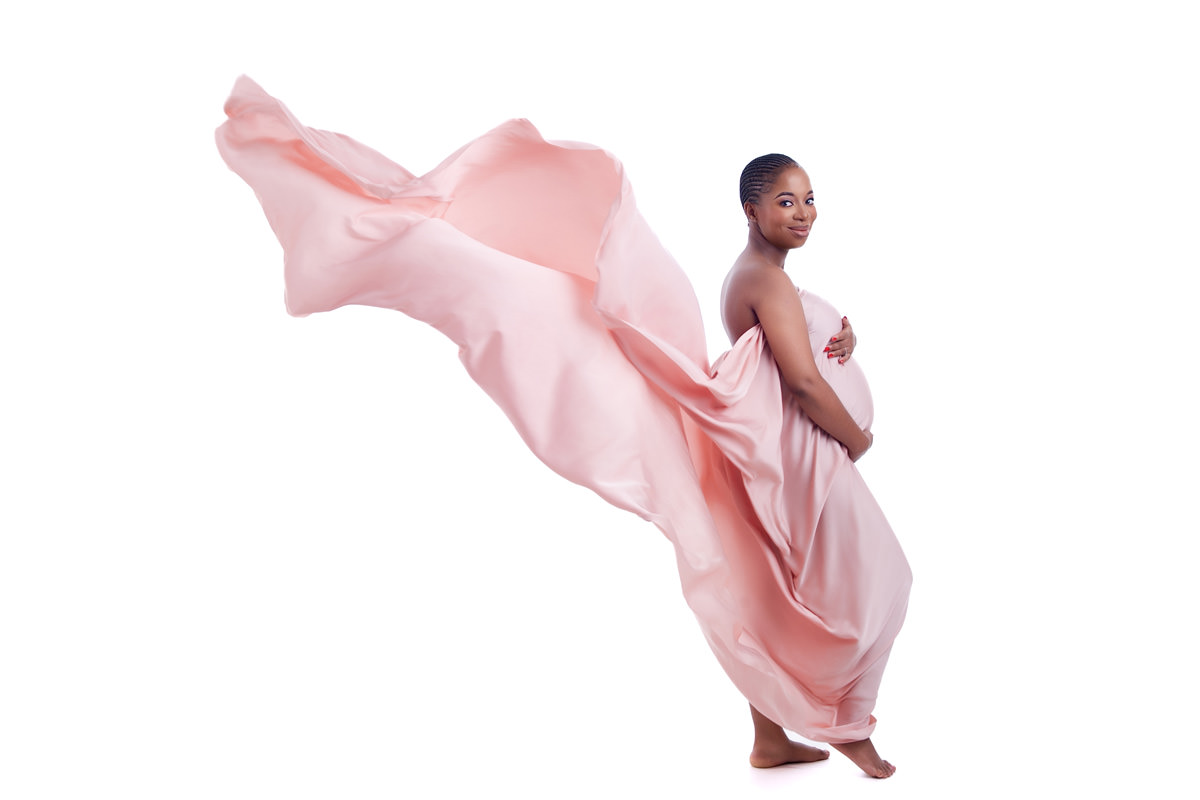 Elegant maternity portrait with soft pink fabric flowing behind an expecting mom, symbolising gentle and supportive care at Pretoria midwife birth centres.