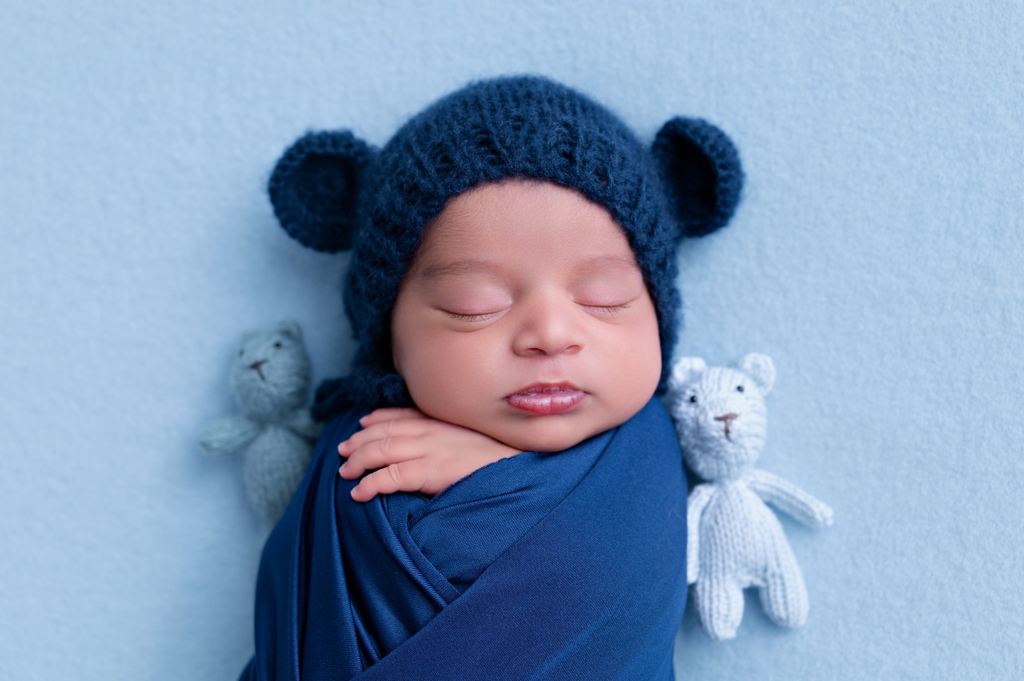 Newborn baby boy wrapped in navy blue with bear bonnet and teddy prop – newborn photographer Pretoria.