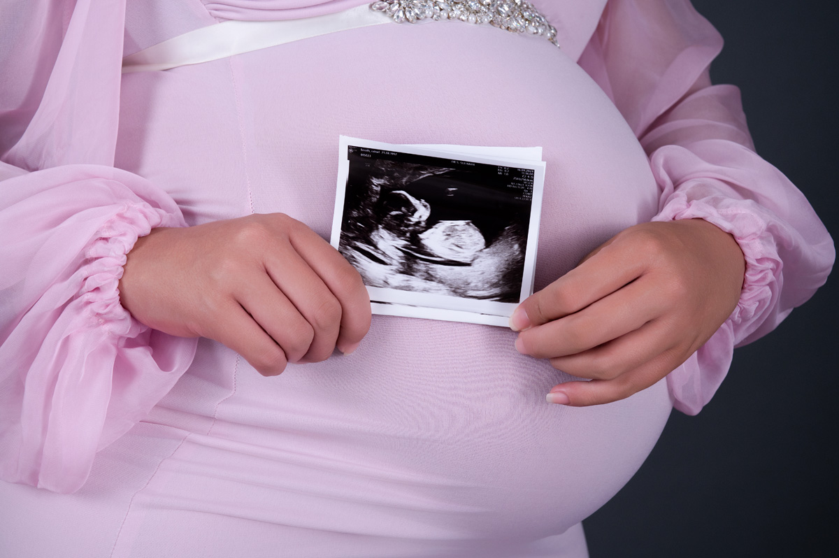 Close-up maternity belly holding ultrasound scan during studio photoshoot – maternity photographer in Pretoria.