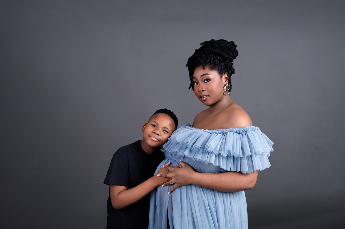 Soft studio maternity photo of mom in blue ruffled dress with her child – maternity photoshoot Pretoria.