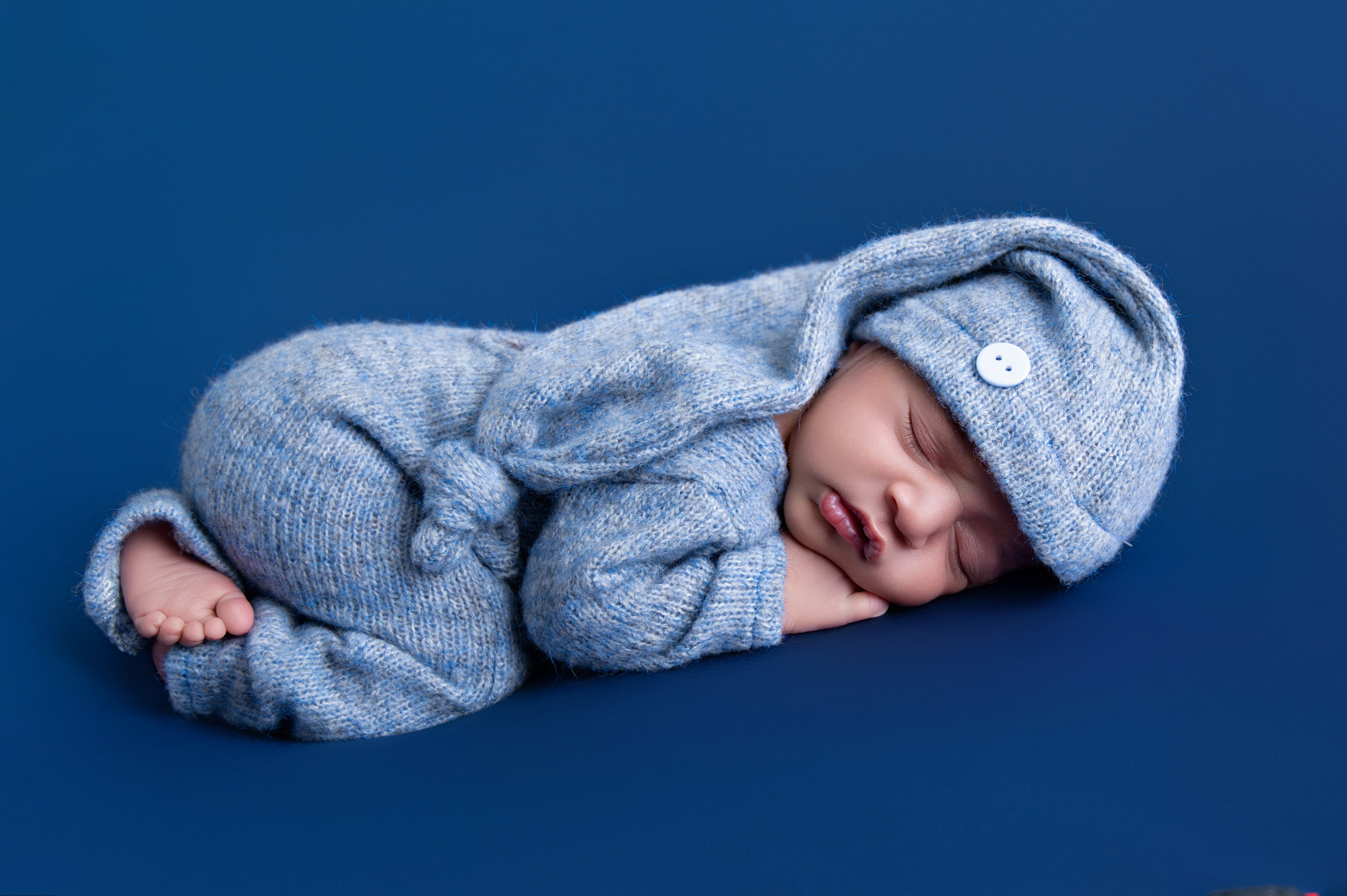 Studio newborn portrait of baby boy wrapped in blue on deep blue backdrop – Pretoria newborn photography.