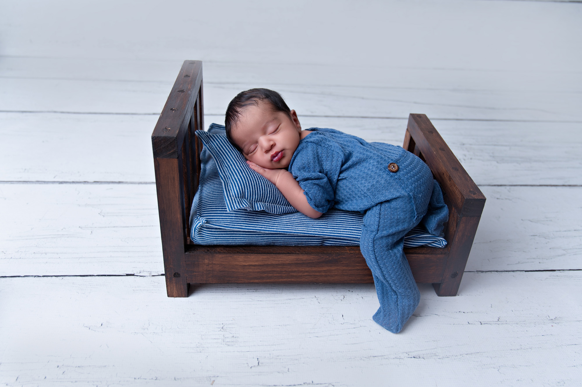 Sleeping newborn boy on rustic wooden bed during studio newborn photoshoot Pretoria.