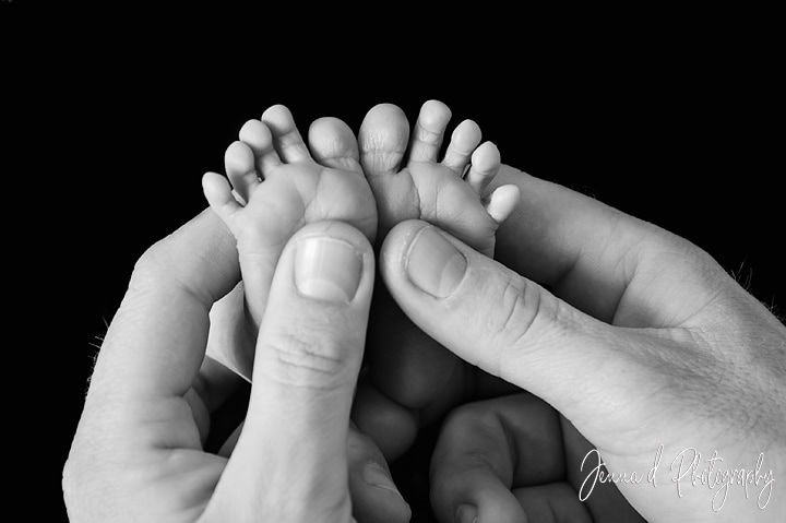 babies feet between daddies hand, black and white photo