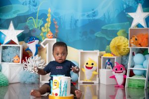 baby shark backdrop, little boy smashing a white cake with baby shark details
