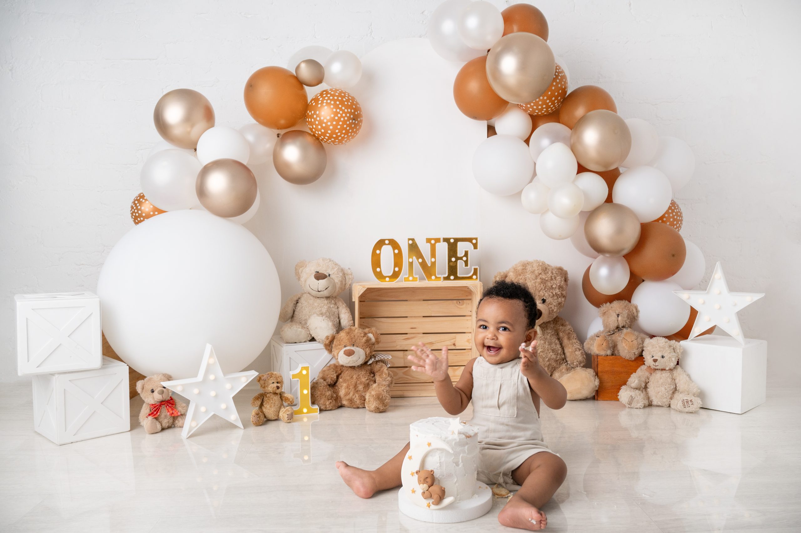 baby boy enjoying a cake smash white balloons, gold balloons, brown balloons