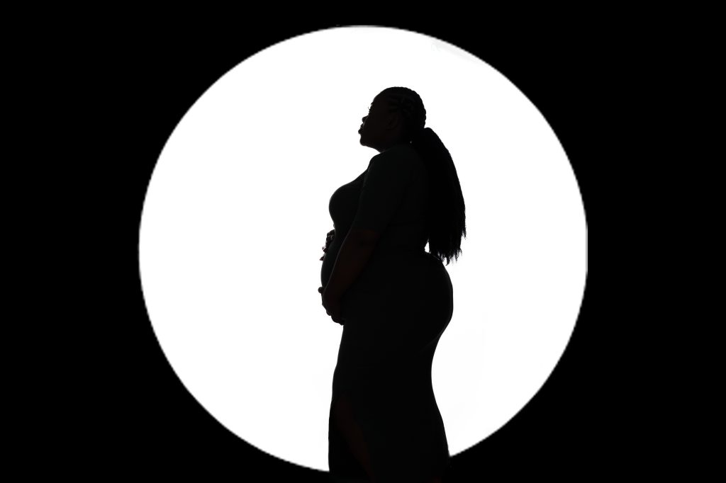Black and white image of pregnant woman in front of a white light