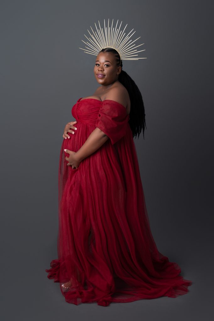 maternity photoshoot showcasing lovley red dress and a gold crown
