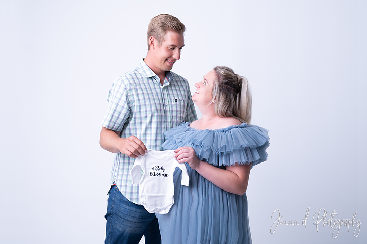 mommy to be and dad with a onsie in studio photos