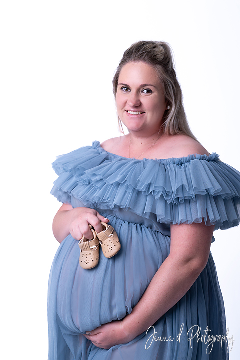 mommy with blue dress in studio with baby shoes as props