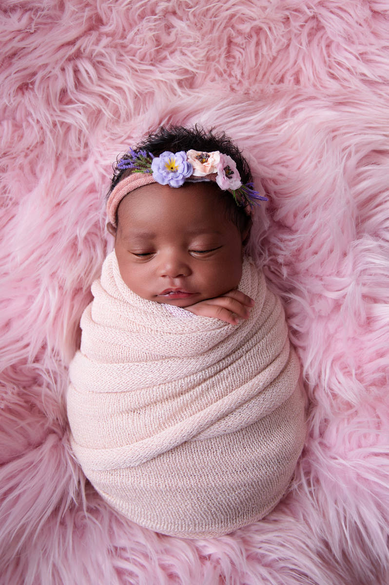 Sleeping newborn baby wrapped in cream on soft pink backdrop, reflecting peaceful outings for new moms searching Baby-Friendly Coffee Shops in Pretoria East.