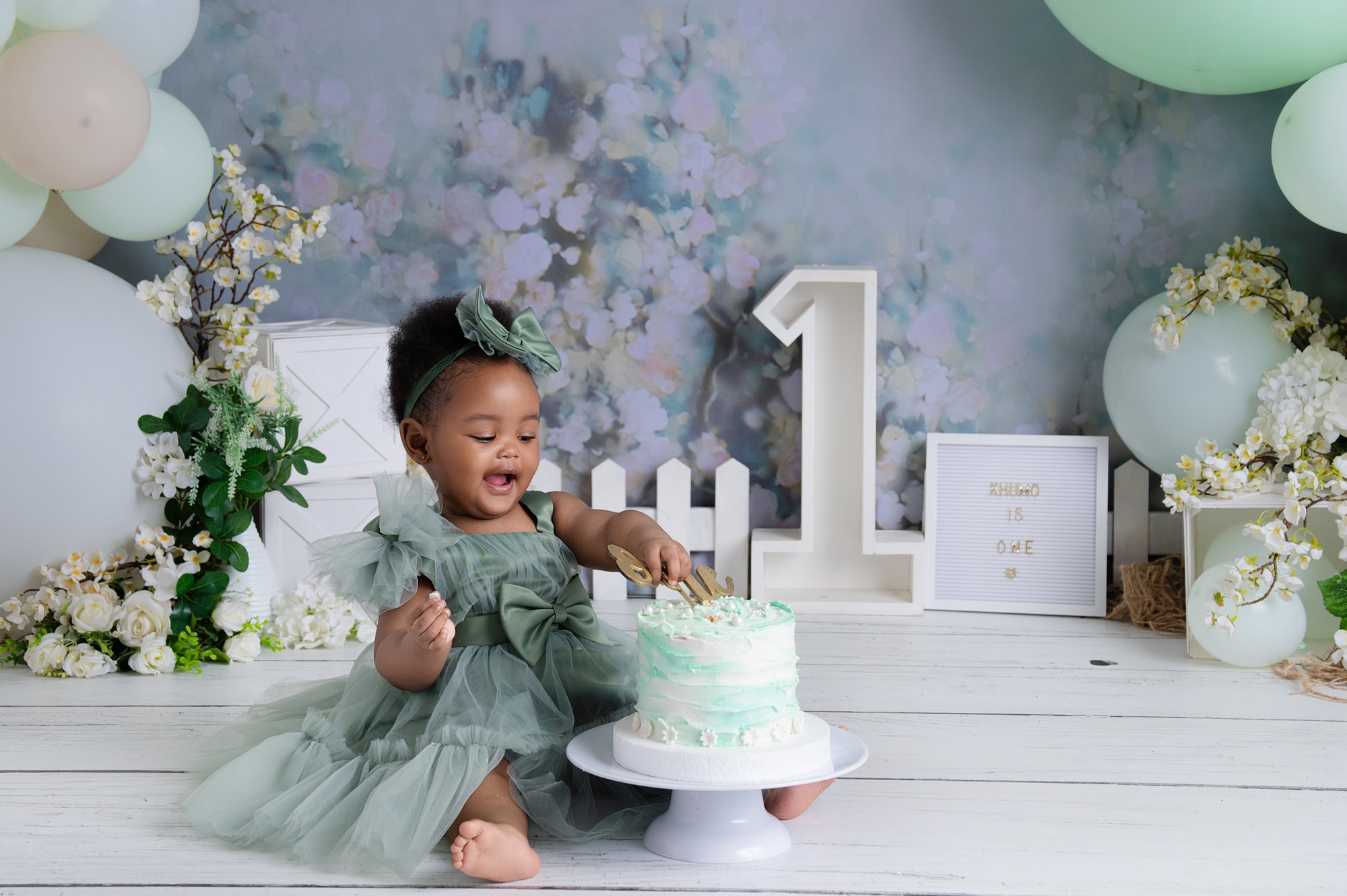 Cake smash moment with baby enjoying mint cake in studio setup – 1st Birthday Cake Midstream.