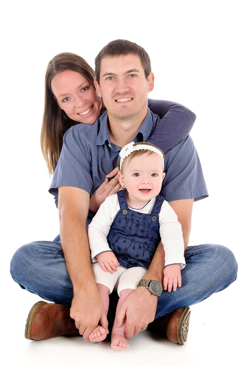 Happy parents sitting with their baby during studio family session, representing considerations when learning how to choose a daycare in Pretoria.
