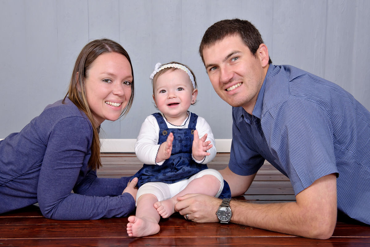 Young family seated together on wooden floor, capturing early family decisions such as how to choose a daycare in Pretoria.