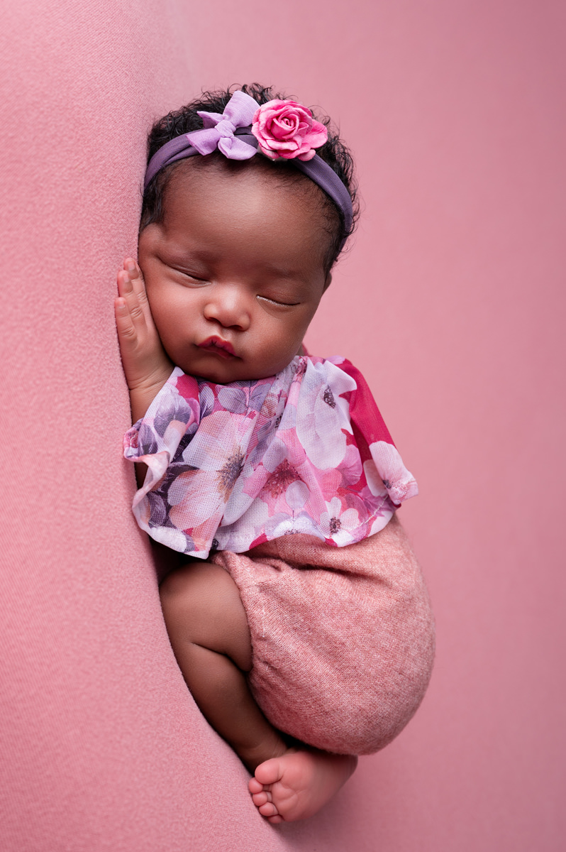 Peaceful newborn baby resting on pink background, capturing the calm of newborn week 1.