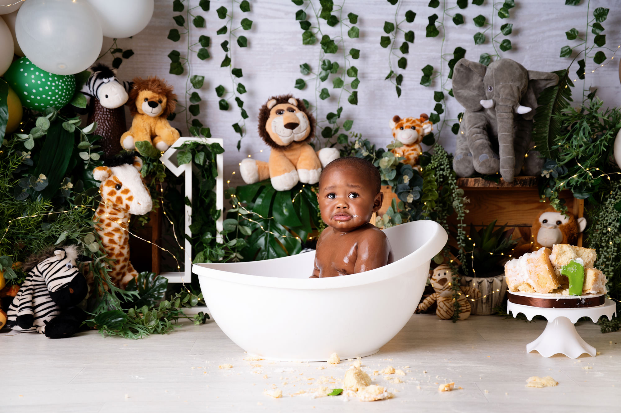Bubble bath after cake smash with baby in white tub and safari decor