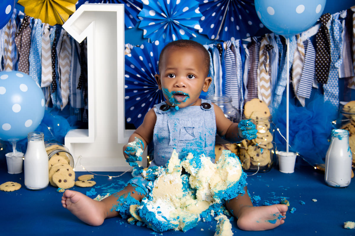 Baby boy sitting with blue cake and number one backdrop during 1st Birthday Cake Pretoria East photoshoot.