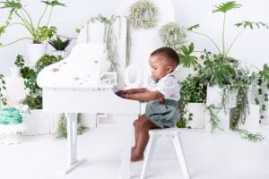 Nkanyezi sitting at a white piano during his cake smash photoshoot in Pretoria.