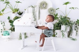 Nkanyezi sitting at a white piano during his cake smash photoshoot in Pretoria.