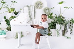Nkanyezi sitting at a white piano during his cake smash photoshoot in Pretoria.