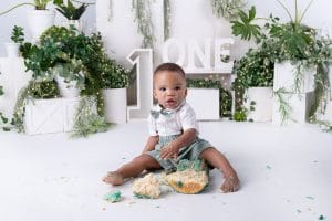 Baby Nkanyezi exploring his birthday cake surrounded by greenery