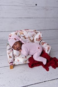 newborn in pink outfit on couch