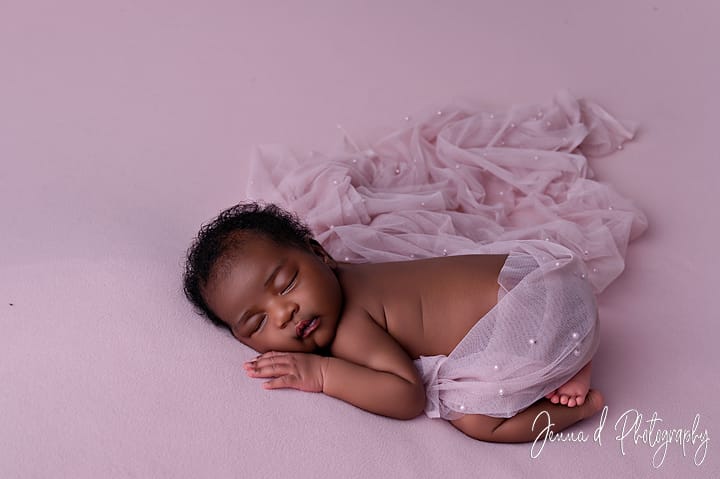 sleepy newborn on pink fabric
