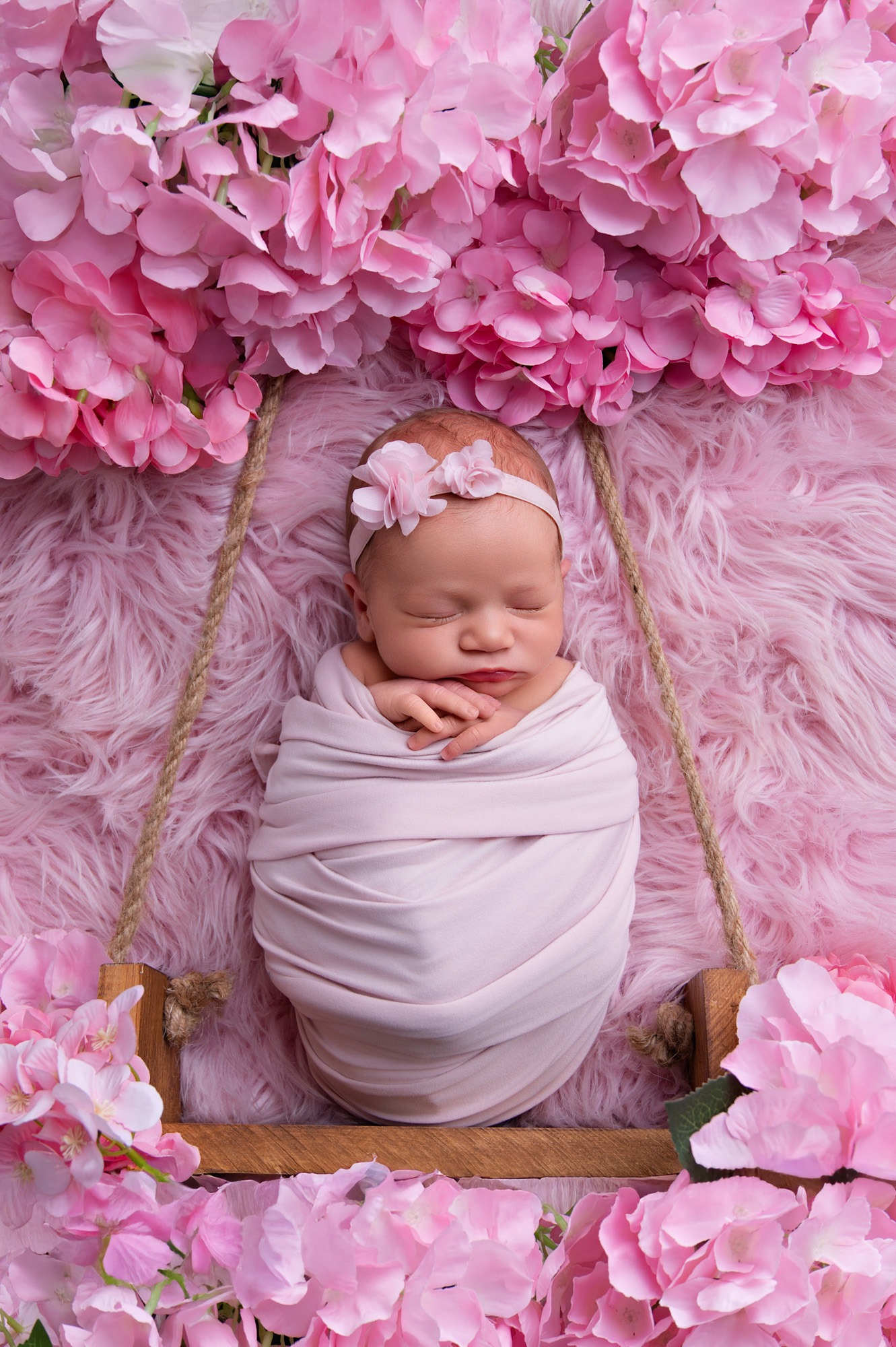 Pretoria newborn photographer capturing a baby girl wrapped in pink with a floral pink backdrop.
