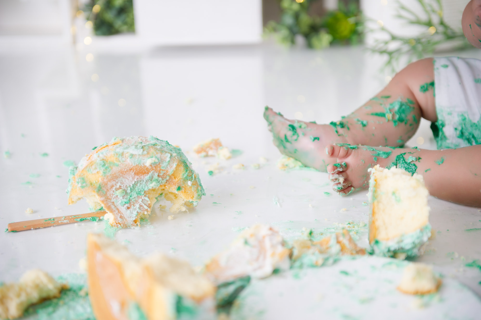 little boy with his feet messed with cake in the studio after his cake smash
