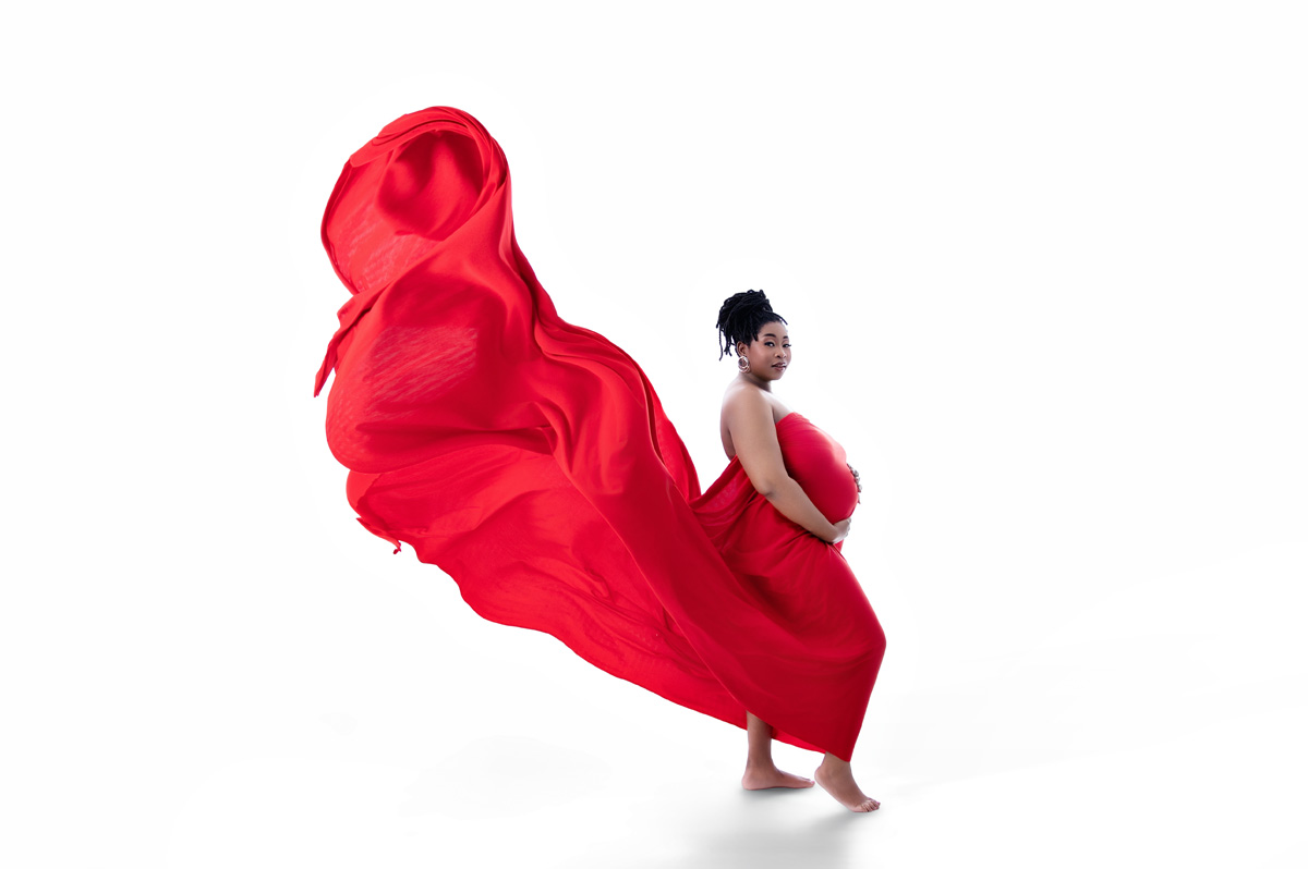 Dramatic maternity photo with flowing red gown on white background – Pretoria studio maternity photography.