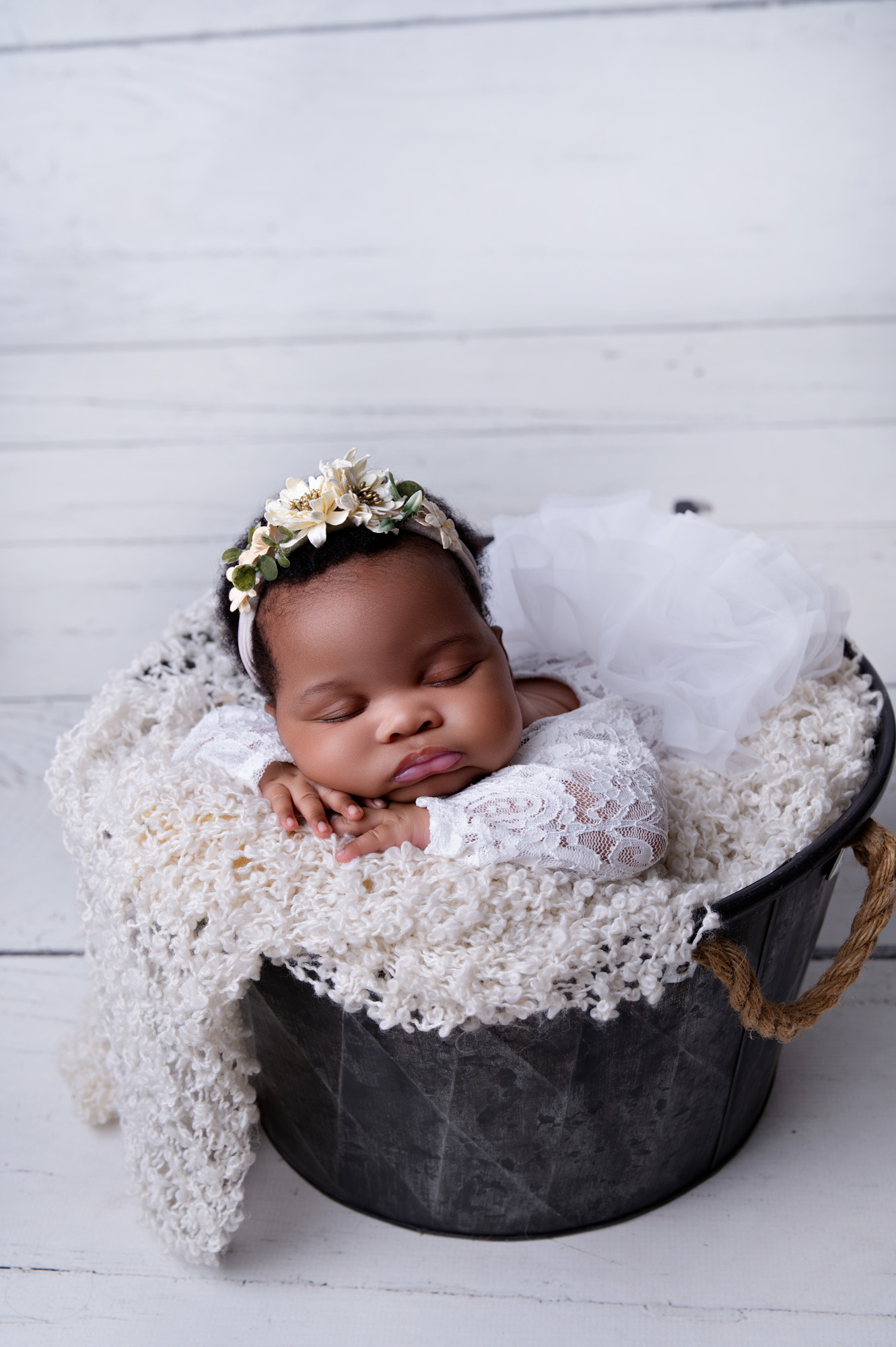 Pretoria newborn photographer capturing a baby girl in a white basket with a cream flokati and floral headband.