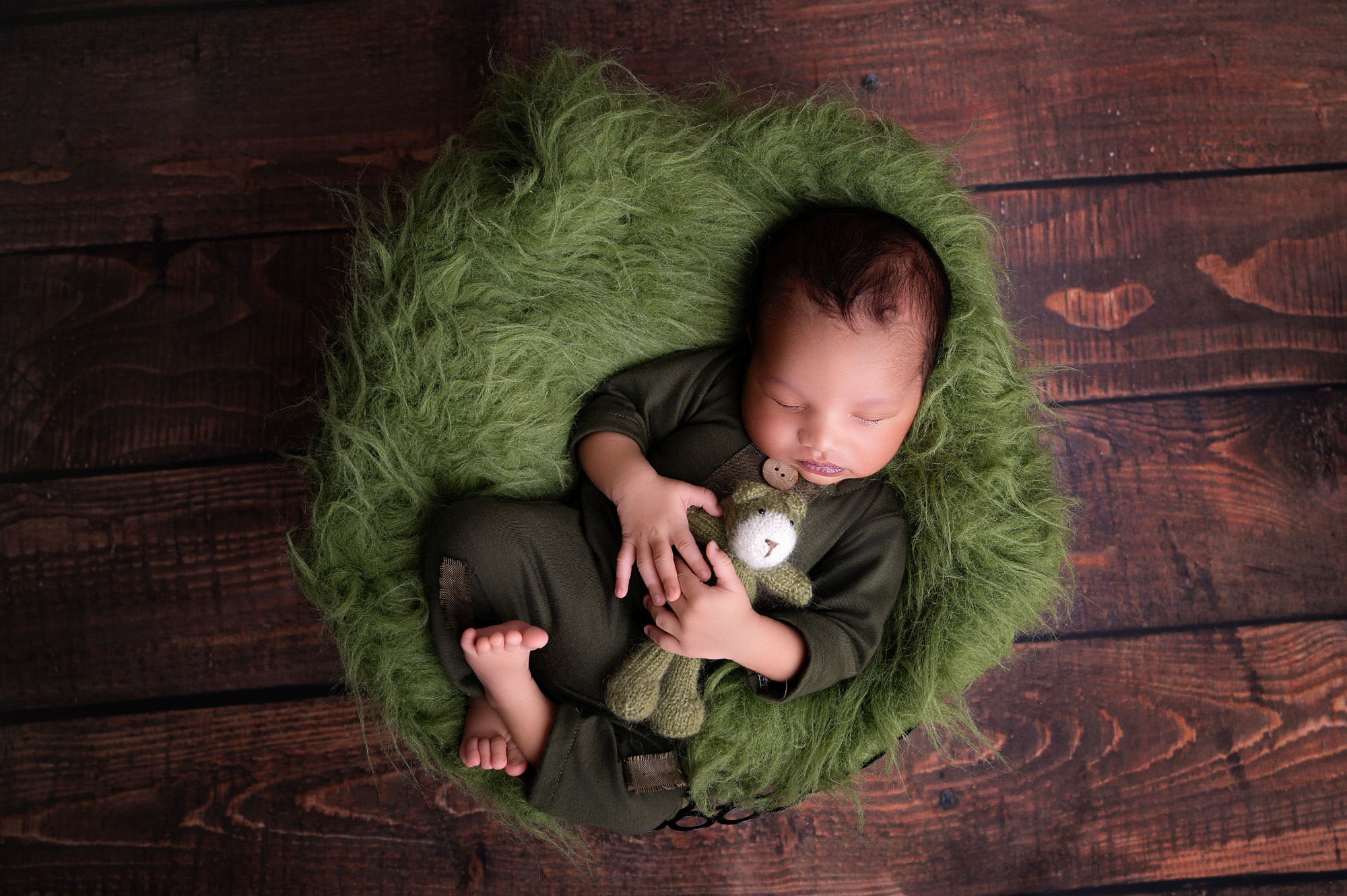 Pretoria newborn photographer session with baby wrapped in dark green on a green flokati blanket.