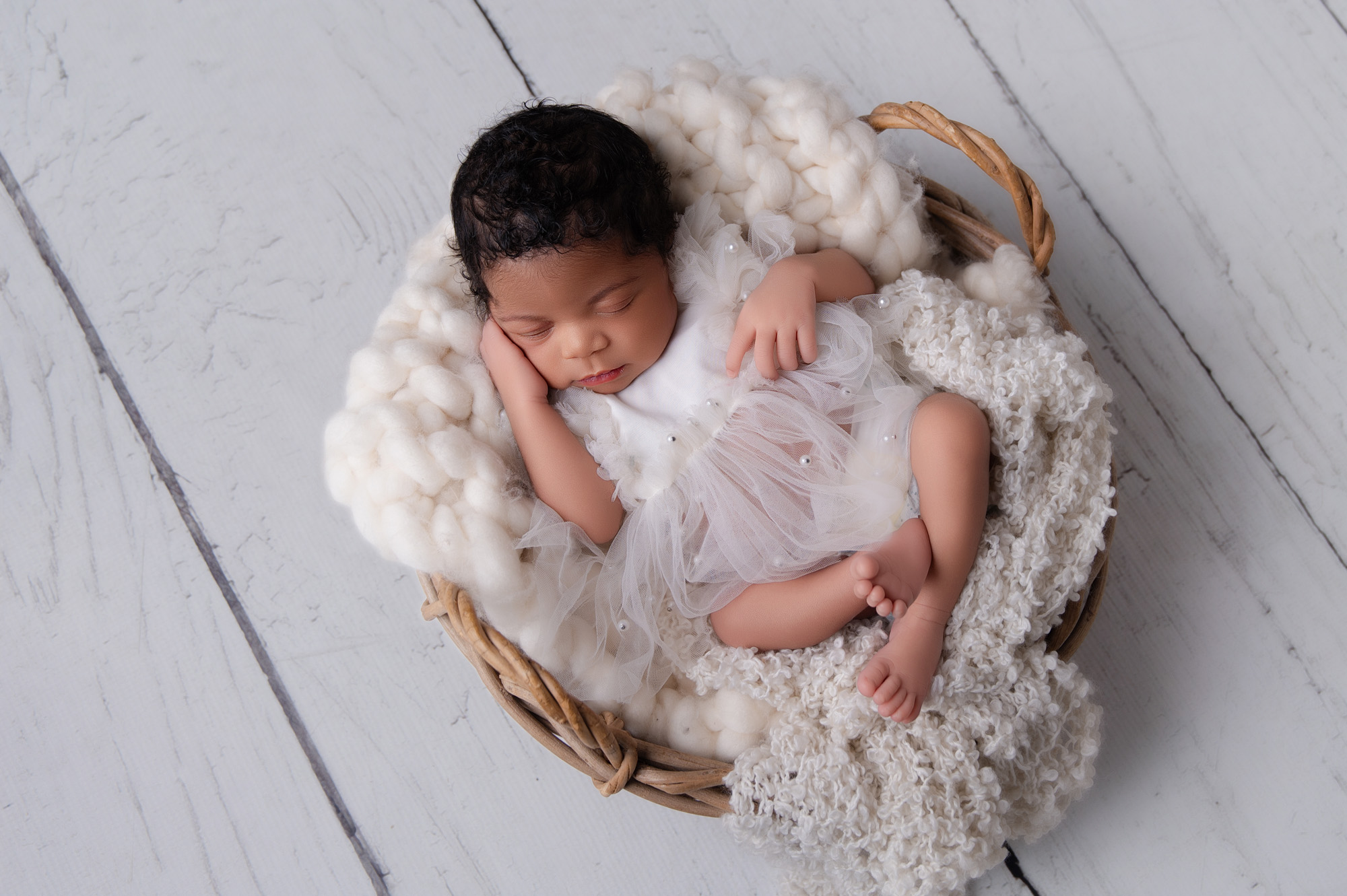 Newborn baby sleeping in a white wrap in a basket — Pretoria newborn photographer studio session.