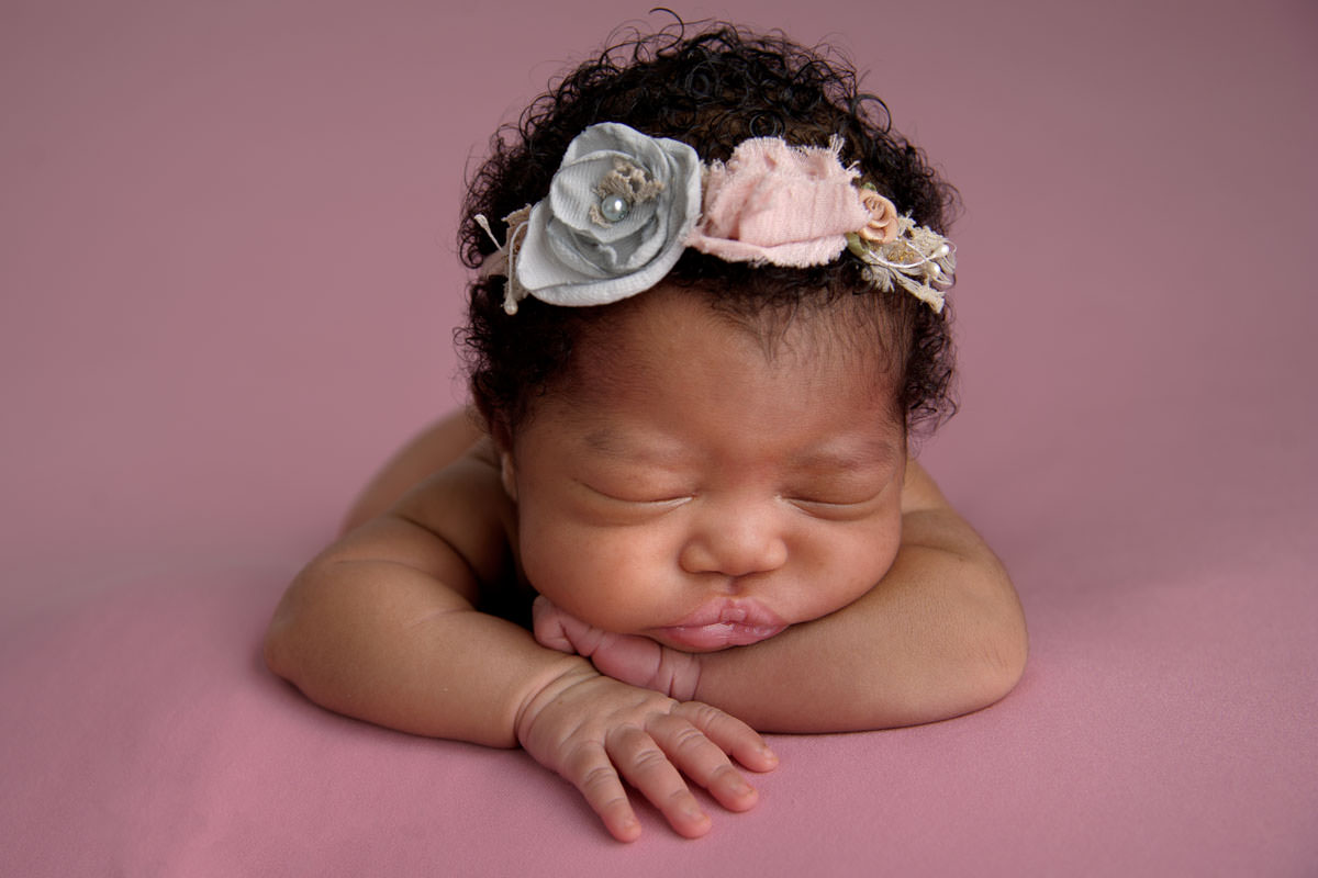 Newborn baby girl resting on tummy in studio portrait