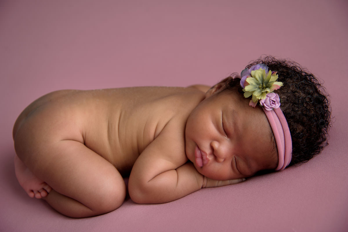 Newborn baby girl curled on side during studio session, representing the calm early stage linked to the best baby sensory classes in Pretoria East.