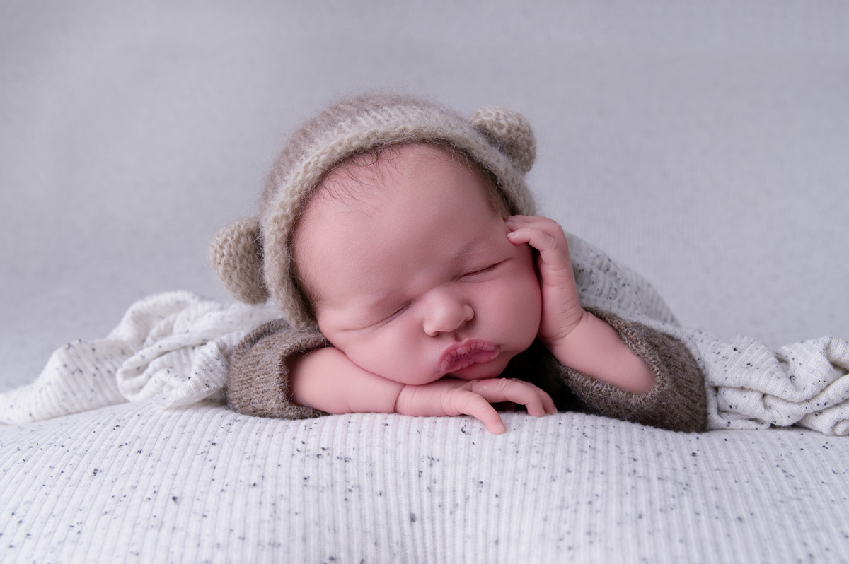 Newborn baby in a knitted bonnet resting comfortably — relatable imagery for parents experiencing breastfeeding problems and struggling to latch.
