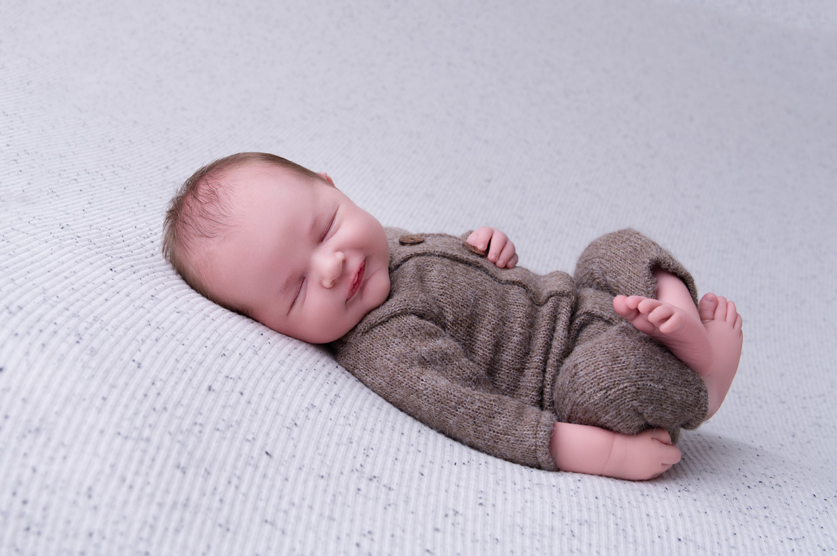 Newborn baby lying on a soft cream blanket — many families seek support for breastfeeding problems and struggling to latch during these early weeks.
