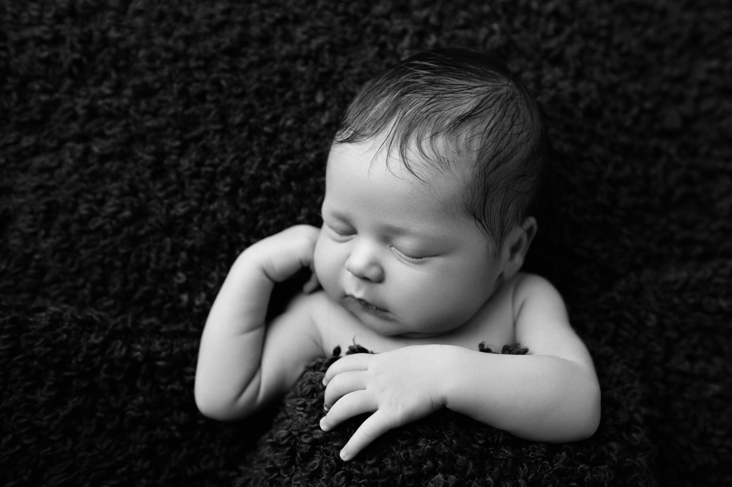 Peaceful newborn portrait on black textured backdrop, representing calm newborn care and breastfeeding in PTA.
