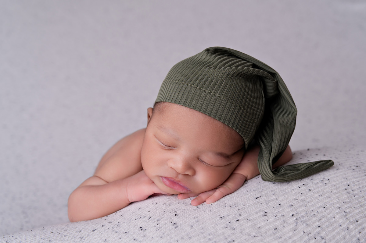 Newborn baby boy sleeping in green sleepy hat on soft blanket,