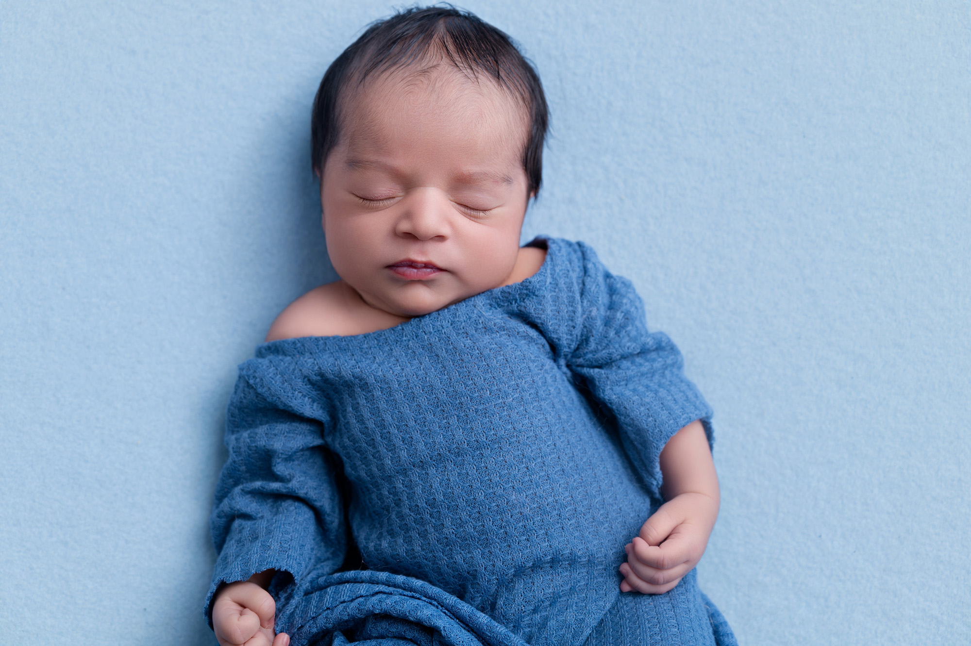 Close-up newborn portrait in blue knitted outfit during studio newborn session – Pretoria newborn photographer.