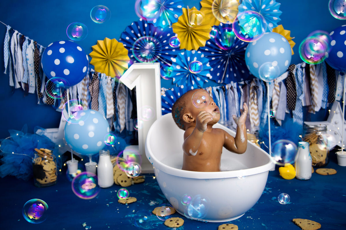 Baby sitting in bubble bath with blue balloons and party decor, celebrating first birthday moments linked to Music Classes for Babies in Pretoria.