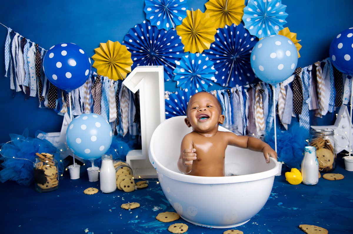 Happy baby laughing in white tub with blue and yellow birthday setup, capturing joyful milestones alongside Music Classes for Babies in Pretoria.