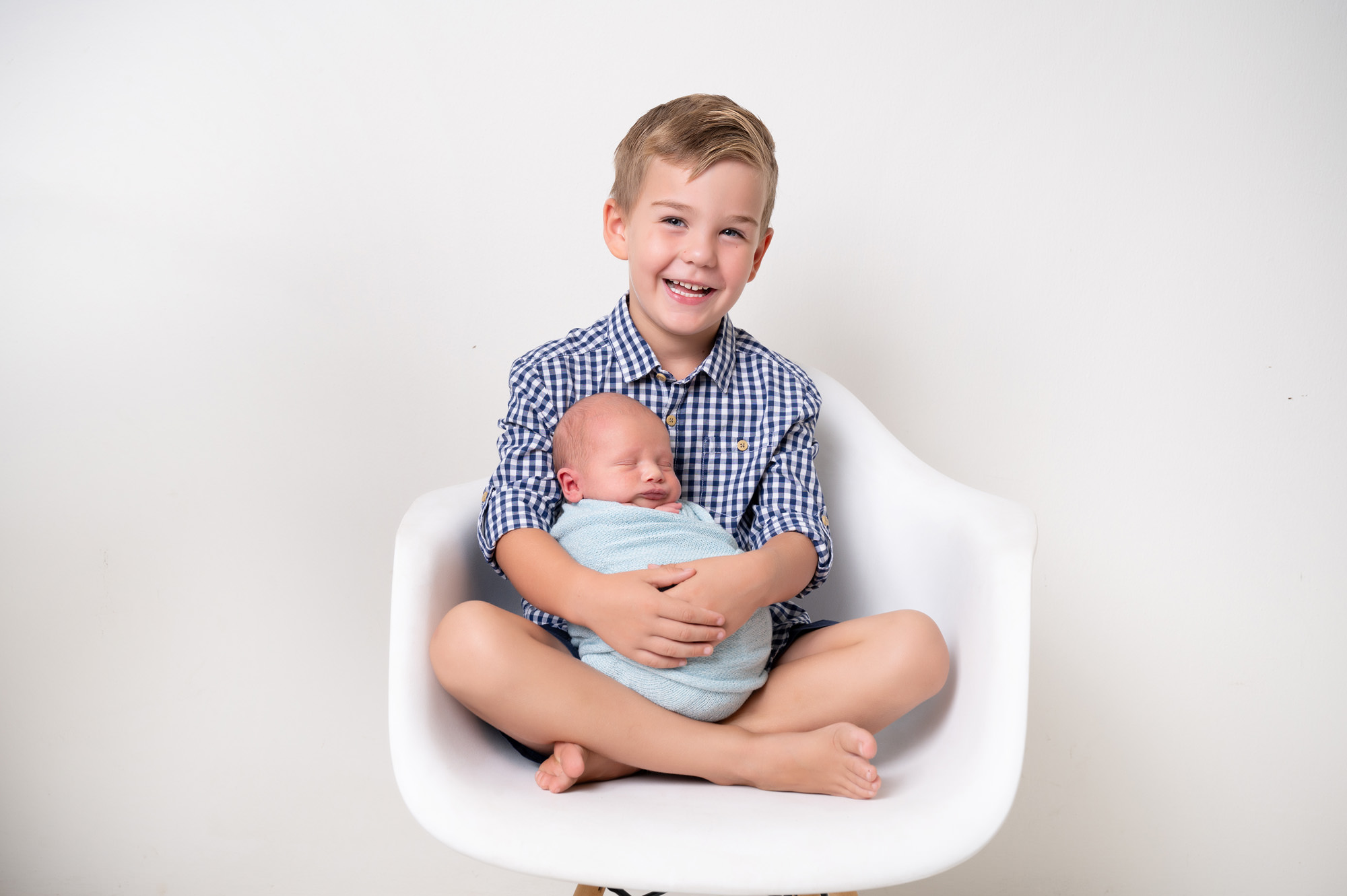 Studio sibling portrait with older brother holding newborn baby, connected to family traditions and Popular baby names South Africa.