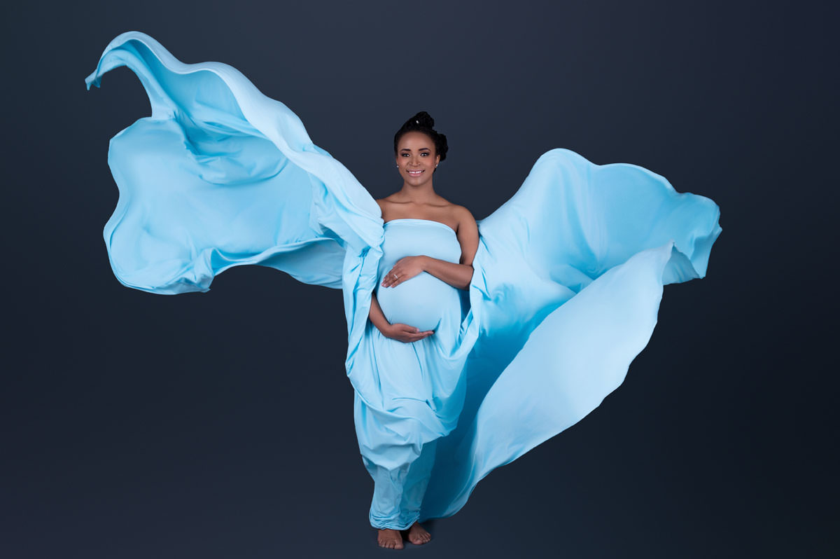 Artistic maternity photoshoot with flowing blue fabric
