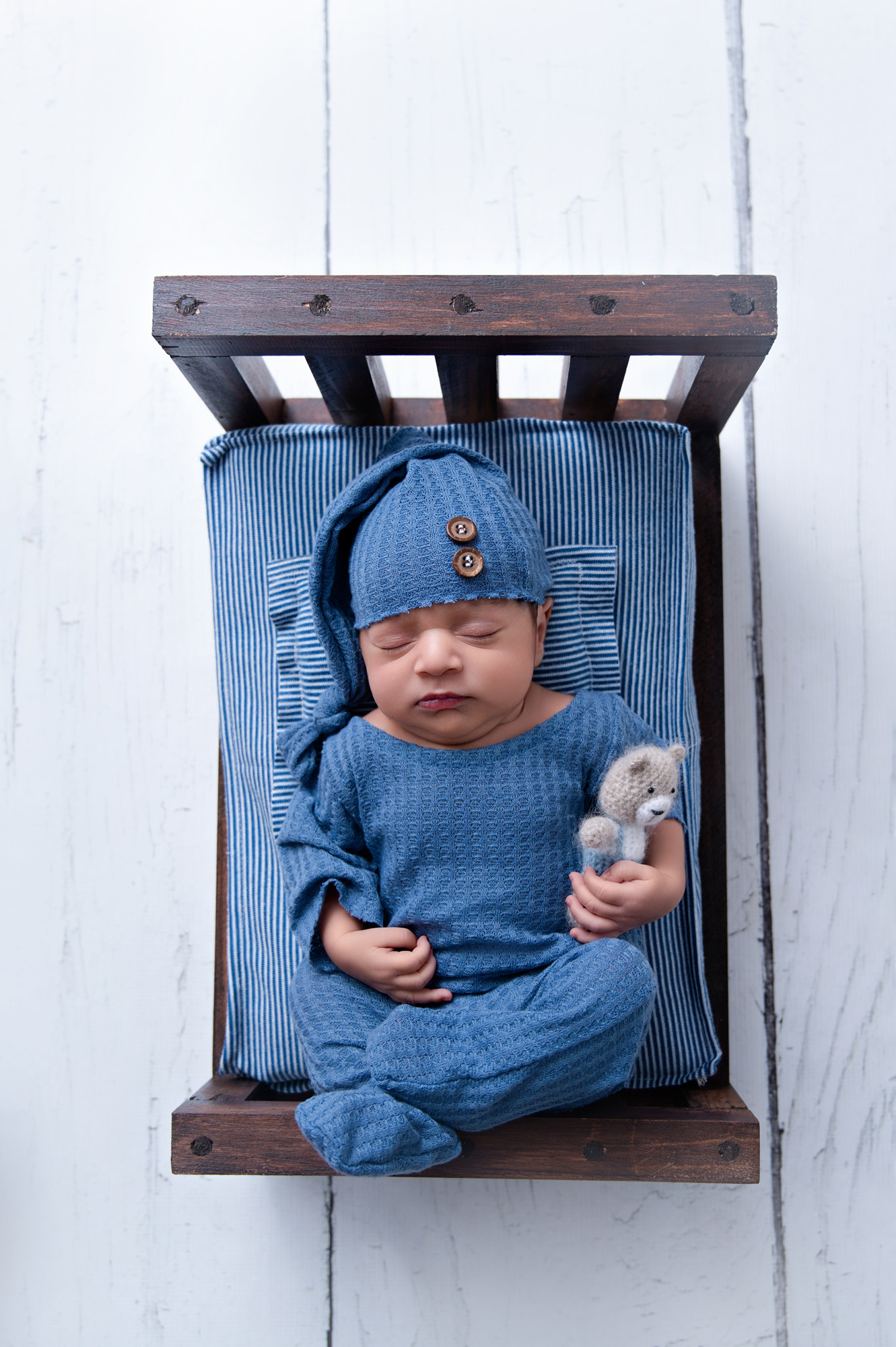 Newborn baby boy wrapped in blue on wooden mini bed with teddy – Pretoria newborn photographer.