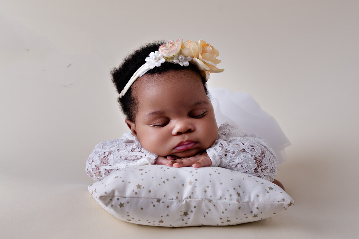 Newborn baby girl sleeping on a white pillow with a yellow flower headband — Pretoria newborn photographer.