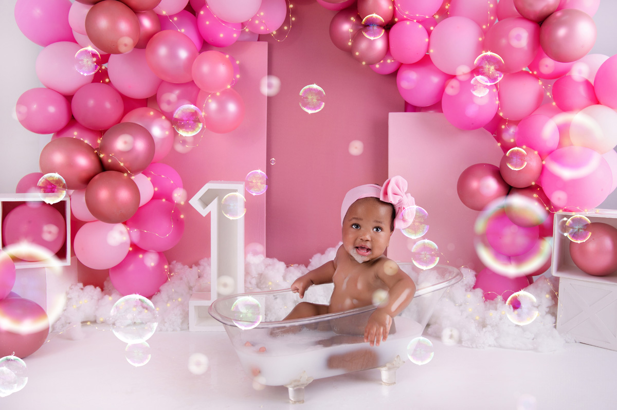 Cute first birthday bubble bath photo with pink balloon backdrop – cake smash photoshoot Pretoria.
